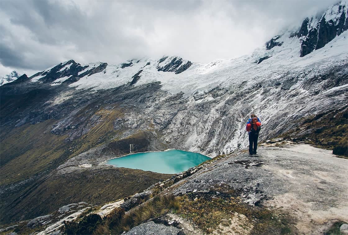 Hiker overlooking turquoise lake in Cordillera Blanca